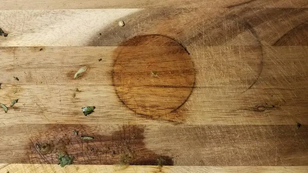 Placa de corte de madeira suja com pedaços de comida e mancha circular — Fotografia de Stock