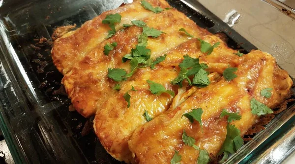 Enchiladas au fromage avec coriandre dans un récipient en verre sur le poêle — Photo