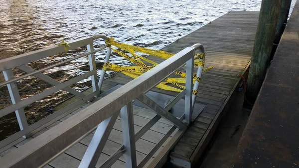 Yellow cauton do not enter tape with wood pier and water — Stock Photo, Image