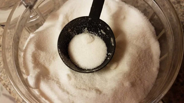 Μαύρο πλαστικό σέσουλα σε γυάλινο δοχείο με λευκή ζάχαρη — Φωτογραφία Αρχείου