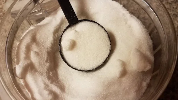 Fekete műanyag kanál üveg tartályban fehér cukorral — Stock Fotó
