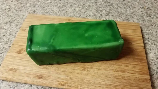 Queijo selado em cera verde na placa de corte de madeira — Fotografia de Stock
