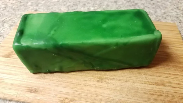 Queijo selado em cera verde na placa de corte de madeira — Fotografia de Stock