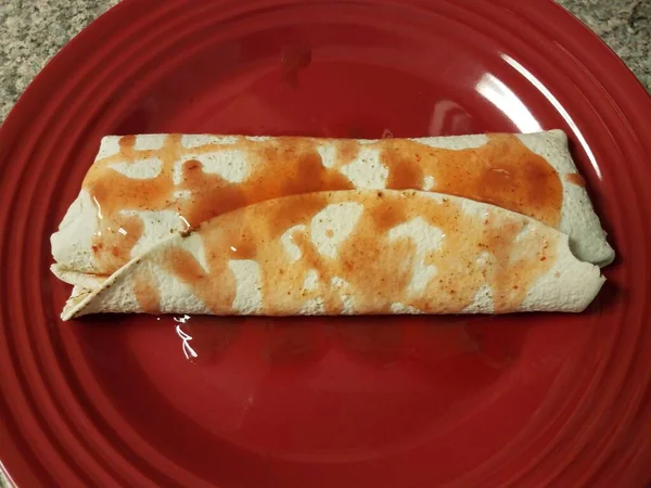 Burrito mit scharfer Sauce auf rotem Teller auf der Theke — Stockfoto