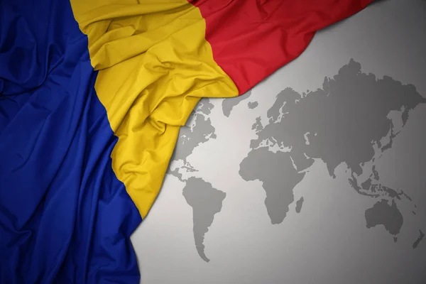 在灰色世界地图背景上挥舞着罗马尼亚多彩的国旗 — 图库照片