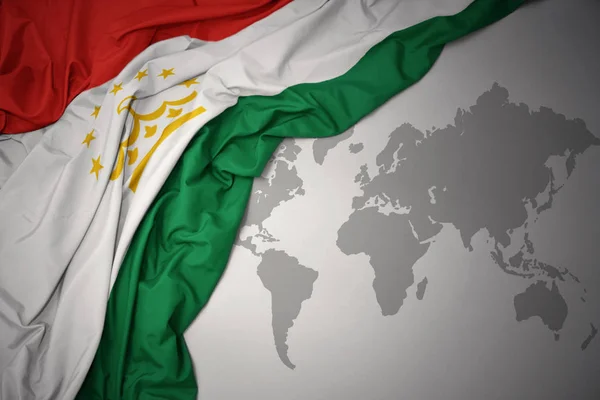 Размахивая Красочным Национальным Флагом Таджикистана Сером Фоне Карты Мира — стоковое фото