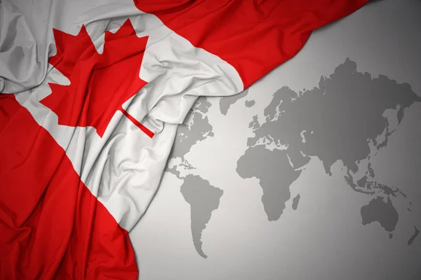 灰色の世界地図背景にカナダのカラフルな国旗を振ってください — ストック写真