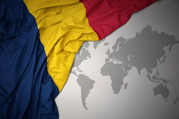 在灰色世界地图背景上挥舞着丰富多彩的乍得国旗 — 图库照片