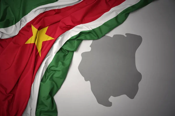 Ondeando Colorida Bandera Nacional Surinam Sobre Fondo Mapa Gris — Foto de Stock
