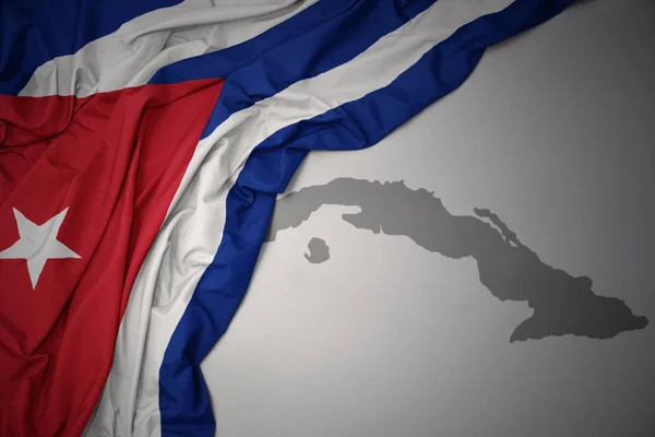 灰色のマップの背景にキューバのカラフルな国旗を振ってください — ストック写真