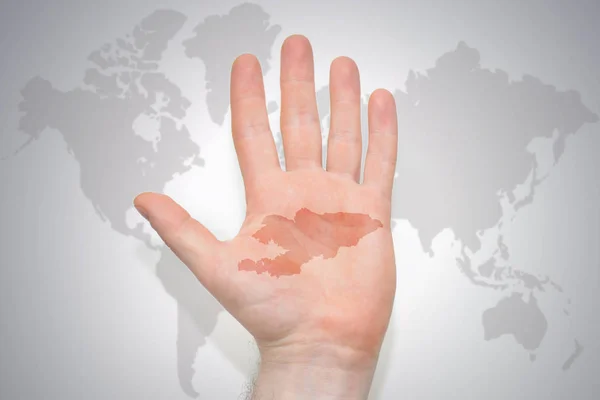 hand with map of kyrgyzstan on the gray world map background. concept