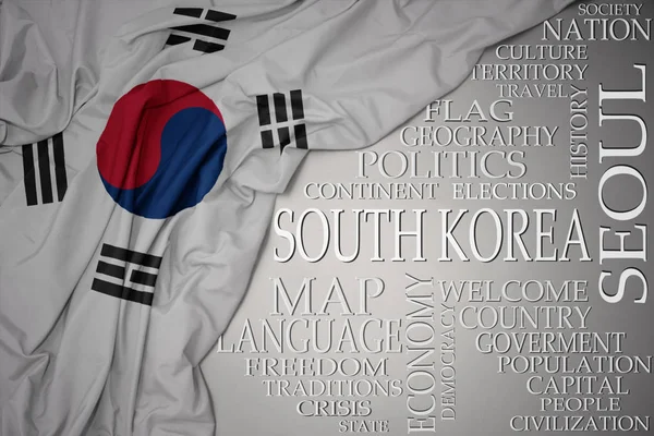 国に関する重要な言葉を背景に、灰色の背景に韓国のカラフルな国旗を振る — ストック写真