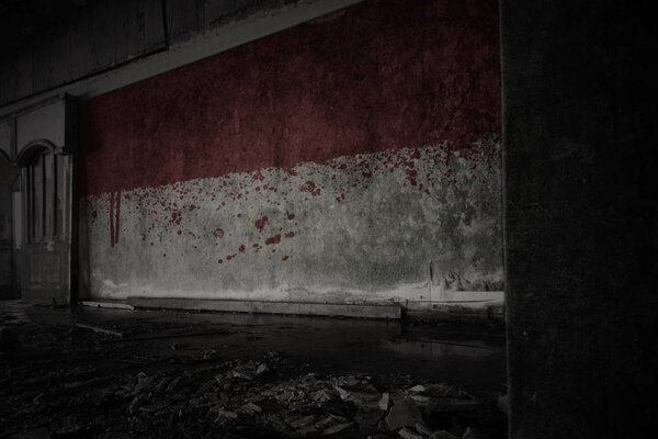 Painted flag of monaco on the dirty old wall in an abandoned ruined house. concept
