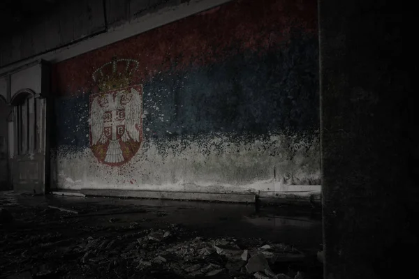 painted flag of serbia on the dirty old wall in an abandoned ruined house.