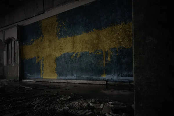 painted flag of sweden on the dirty old wall in an abandoned ruined house.