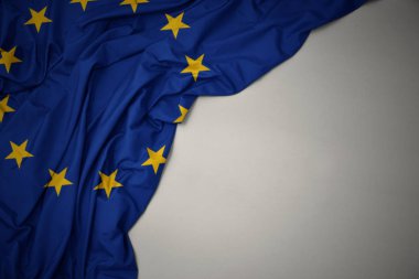 gri bir arka planda Avrupa Birliği Ulusal bayrağı sallayarak.