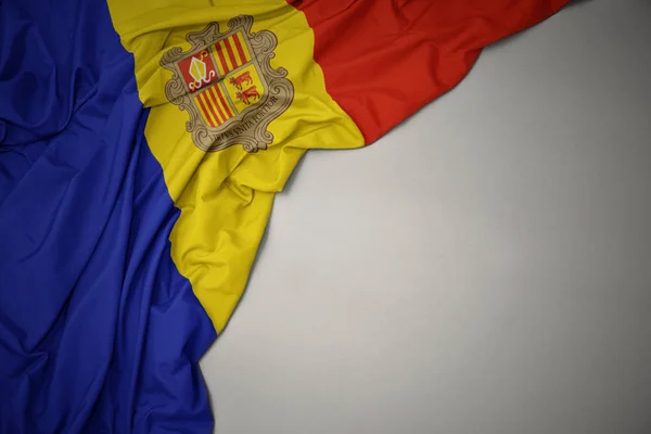 Agitant le drapeau national de l'andorre sur un fond gris . — Photo