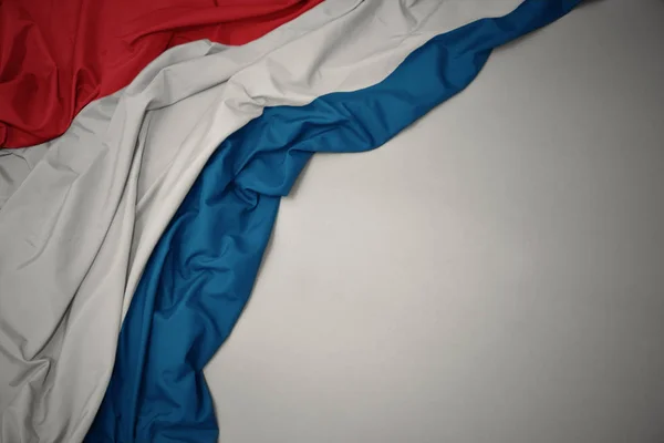 Ondeando la bandera nacional de Luxemburgo sobre un fondo gris . —  Fotos de Stock