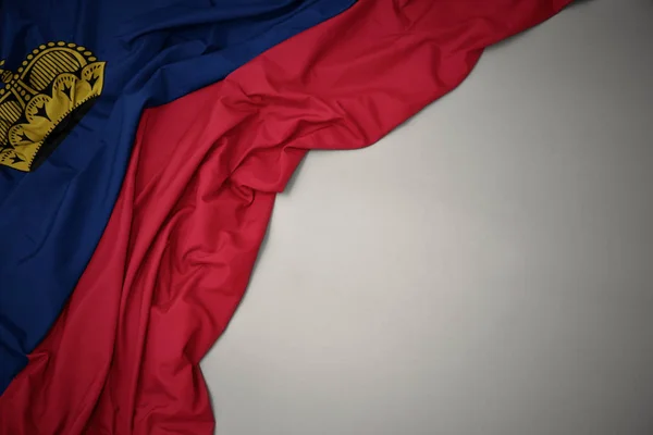 Integetett Liechtenstein nemzeti zászlaja szürke háttér. — Stock Fotó