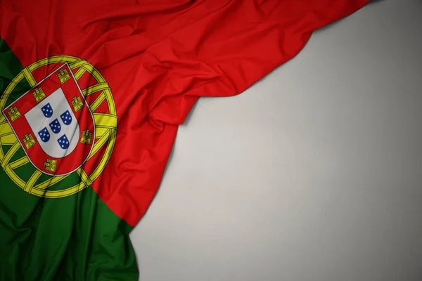 Schwenken der portugiesischen Nationalflagge auf grauem Hintergrund. — Stockfoto