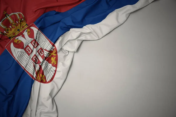 Ondeando la bandera nacional de serbia sobre un fondo gris . —  Fotos de Stock