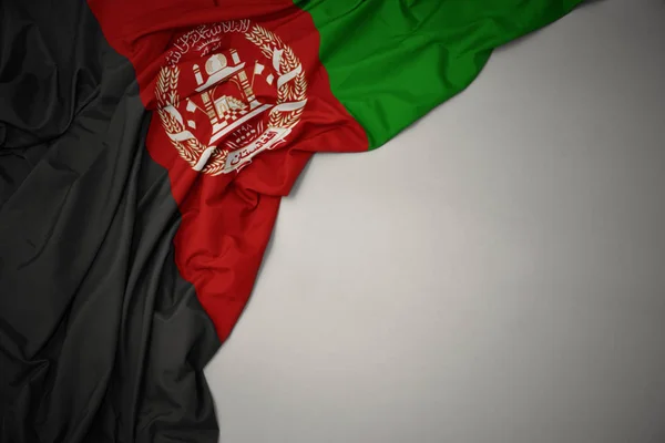 Zwaaiende nationale vlag van Afghanistan op een grijze achtergrond. — Stockfoto