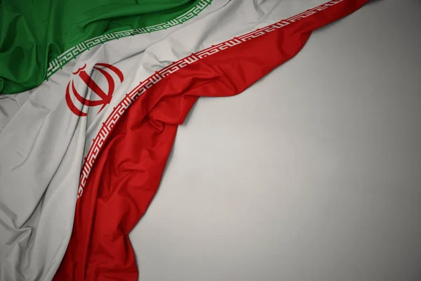 Sventolando bandiera nazionale di iran su sfondo grigio . — Foto Stock