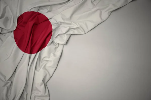 Ondeando la bandera nacional de Japón sobre un fondo gris . —  Fotos de Stock