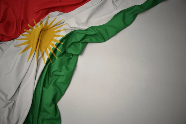 Sventolando bandiera nazionale del kurdistan su sfondo grigio . — Foto Stock