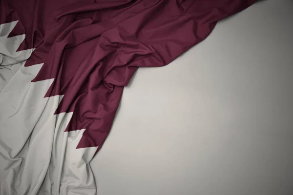 Nationalflagge Katars auf grauem Hintergrund schwenkend. — Stockfoto