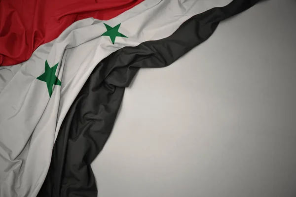 Ondeando la bandera nacional de Siria sobre un fondo gris . —  Fotos de Stock