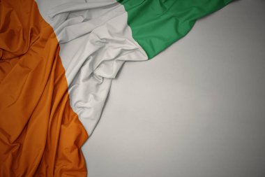 gri bir arka plan üzerinde cote divoire ulusal bayrak sallayarak.