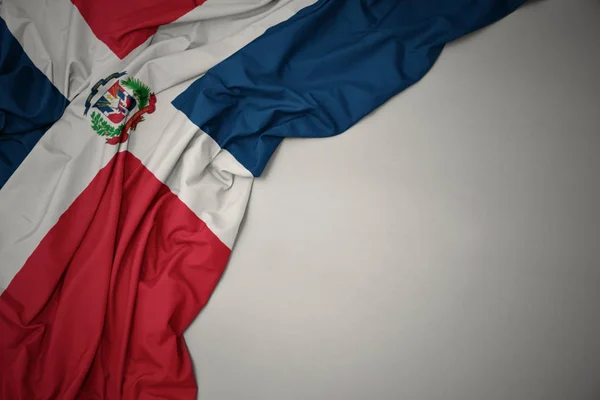 Nationalflagge der Dominikanischen Republik auf grauem Hintergrund schwenkend. — Stockfoto