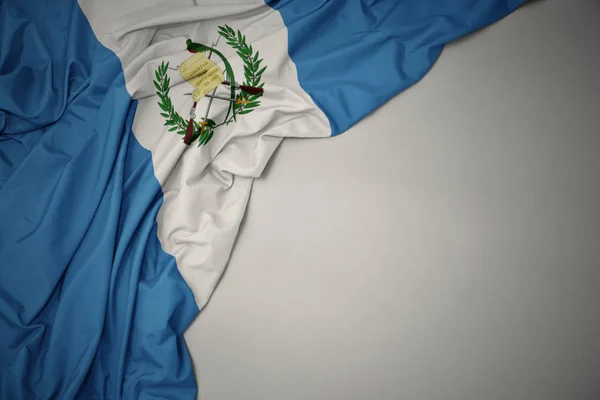 Mávající národní vlajku Guatemaly na šedém pozadí. — Stock fotografie