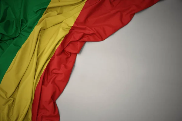 Zwaaiende nationale vlag van de Republiek Congo op een grijze achtergrond. — Stockfoto