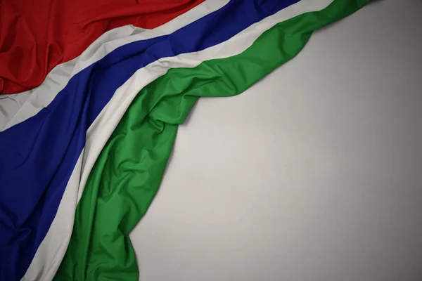 Agitant le drapeau national de la Gambie sur un fond gris . — Photo