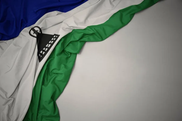 Ondeando la bandera nacional de lesotho sobre un fondo gris . —  Fotos de Stock