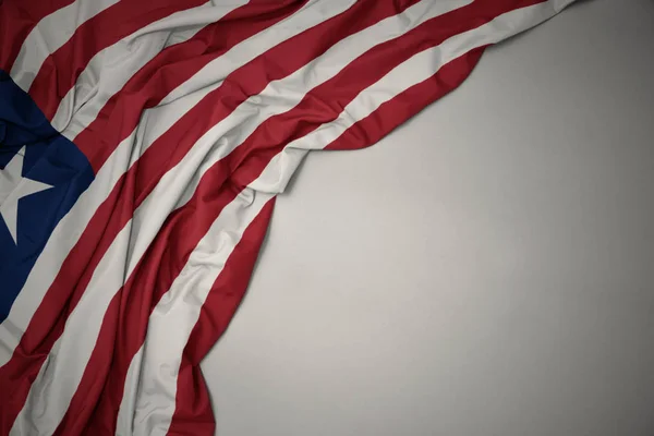 Ondeando la bandera nacional de Liberia sobre un fondo gris . — Foto de Stock