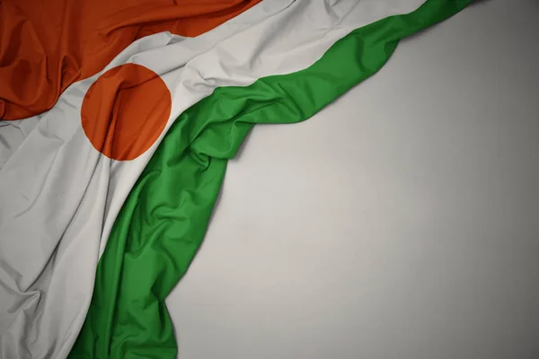 Sventolando bandiera nazionale di niger su uno sfondo grigio . — Foto Stock