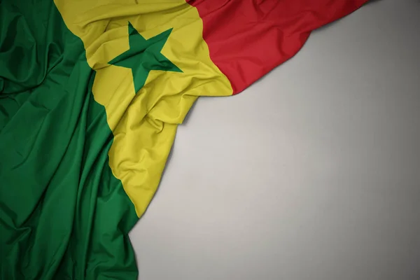 Das Schwenken der senegalesischen Nationalflagge auf grauem Hintergrund. — Stockfoto