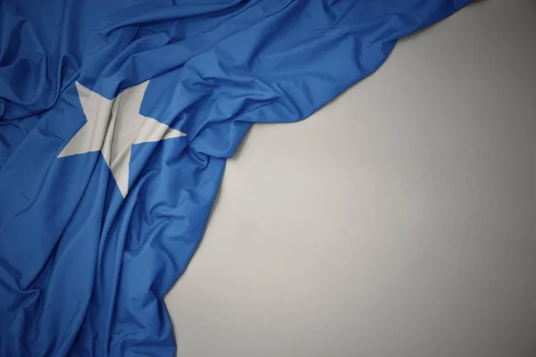 Melambaikan bendera nasional somalia dengan latar belakang abu-abu . — Stok Foto