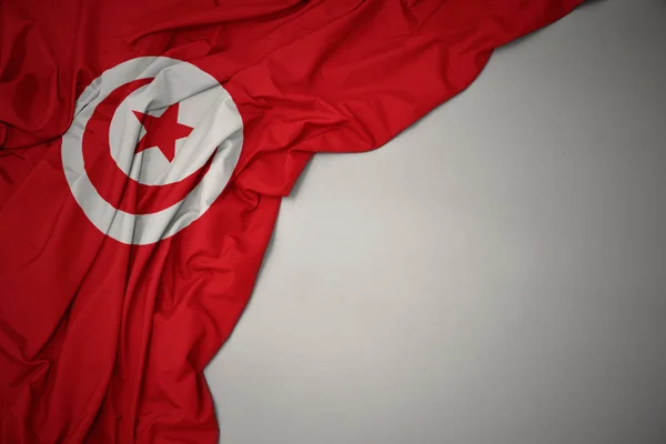 Waving national flag of tunisia on a gray background. — Stock Photo, Image