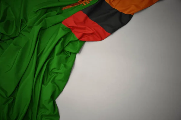 Ondeando la bandera nacional de zambia sobre un fondo gris . —  Fotos de Stock