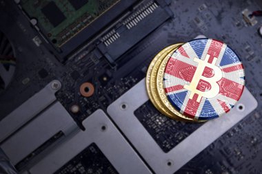 bir bilgisayar elektronik devre kartı üzerinde büyük Britanya bayrağı ile altın bitcoins. bitcoin madencilik kavramı.