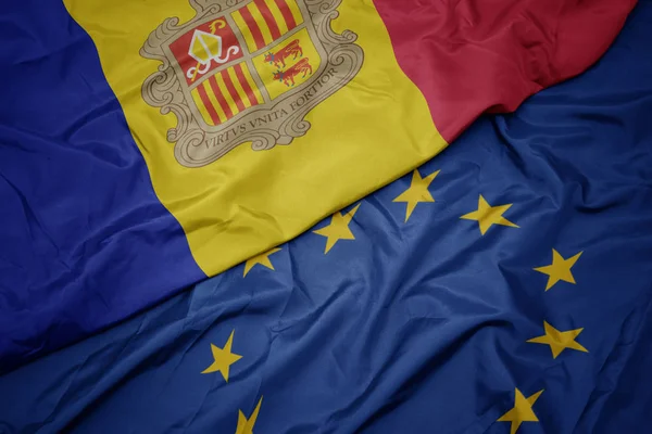 Zwaaiende kleurrijke vlag van de Europese Unie en de vlag van Andorra. — Stockfoto