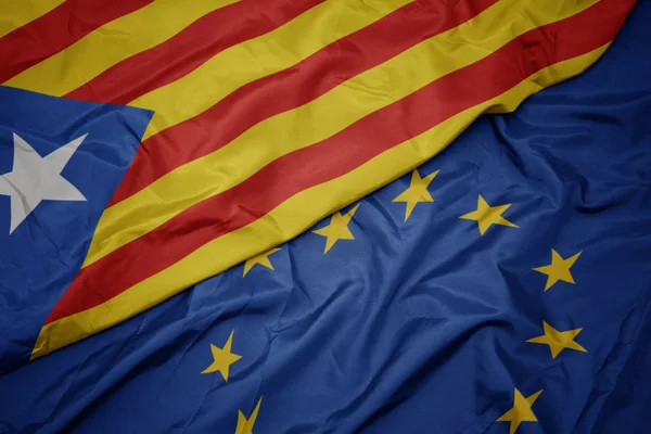 Zwaaiende kleurrijke vlag van de Europese Unie en de nationale vlag van Catalonië. — Stockfoto