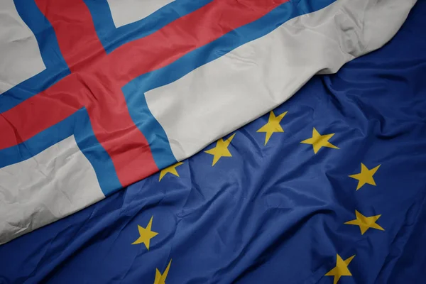 Agitant le drapeau coloré de l'Union européenne et le drapeau national des îles Féroé . — Photo