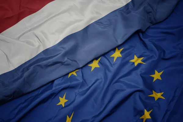 Macha kolorowy flaga Unii Europejskiej i Flaga narodowa Holandii. — Zdjęcie stockowe