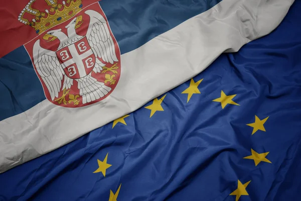 Ondeando colorida bandera de la unión europea y la bandera nacional de serbia . —  Fotos de Stock