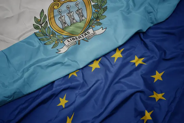 Viftande färgglada flagga av Europeiska unionen och nationella flaggan San Marino. — Stockfoto